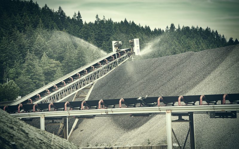 Mining conveyor with dust-suppression sprinklers over a gravel stockpile