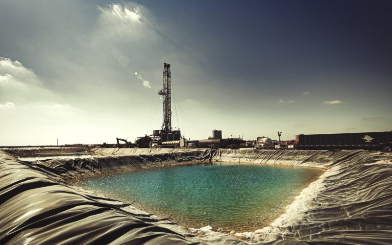Drill rig beside a lined reserve pit