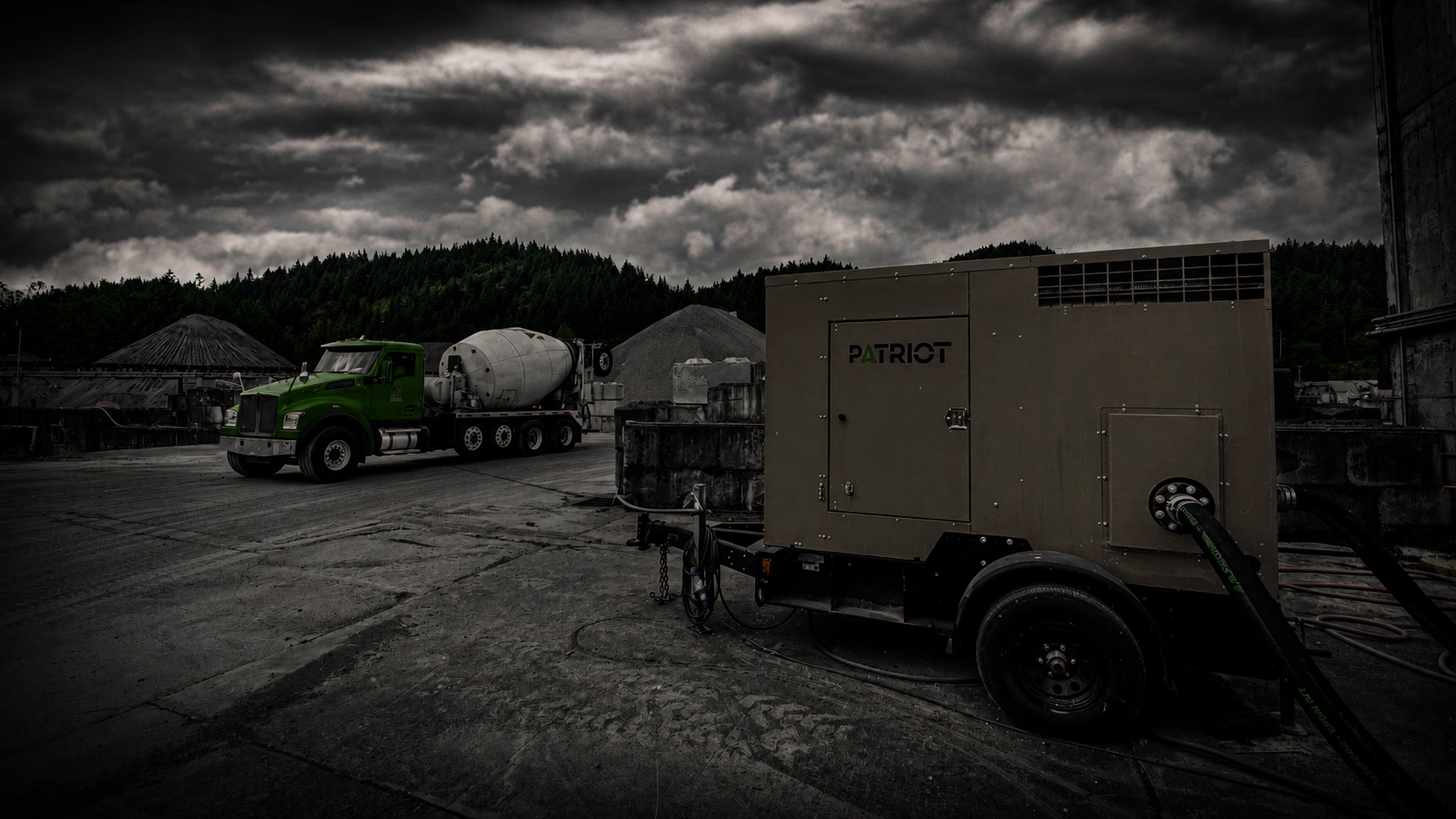 Patriot pump unit staged at a Knife River aggregate quarry as a cement mixer truck passes under a stormy sky