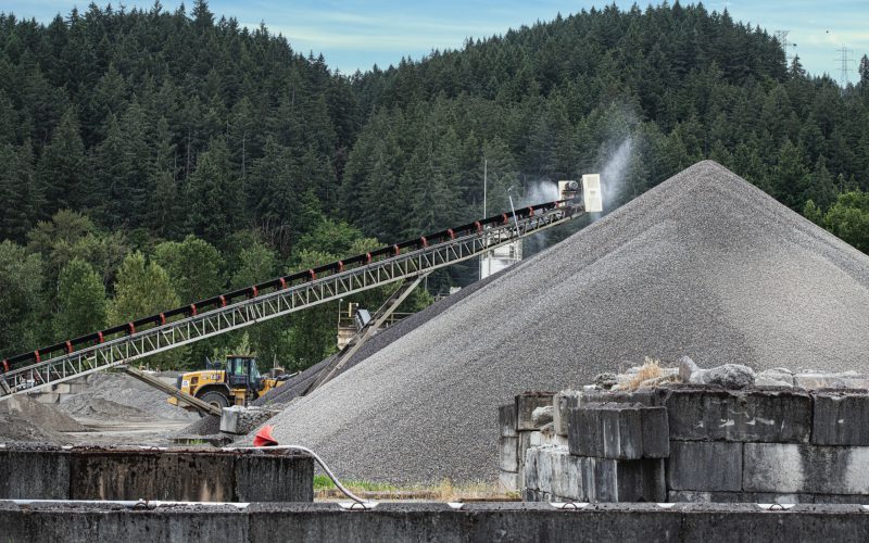 Wheel loader and conveyor working gravel stockpiles at an aggregate site