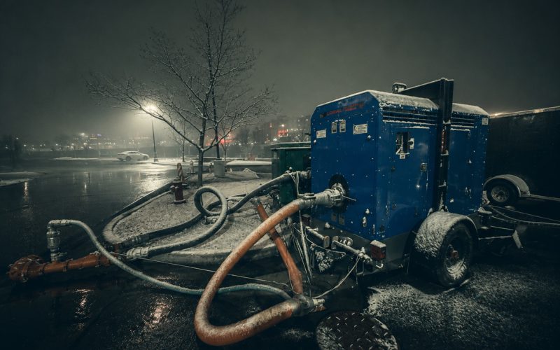Pump package running a street bypass into a manhole on a wet night