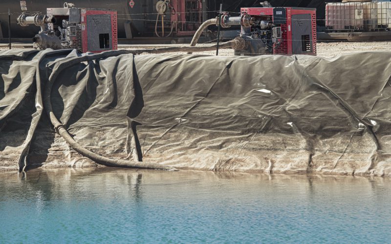Patriot pump units transferring water at a lined pit on a West Texas drilling site
