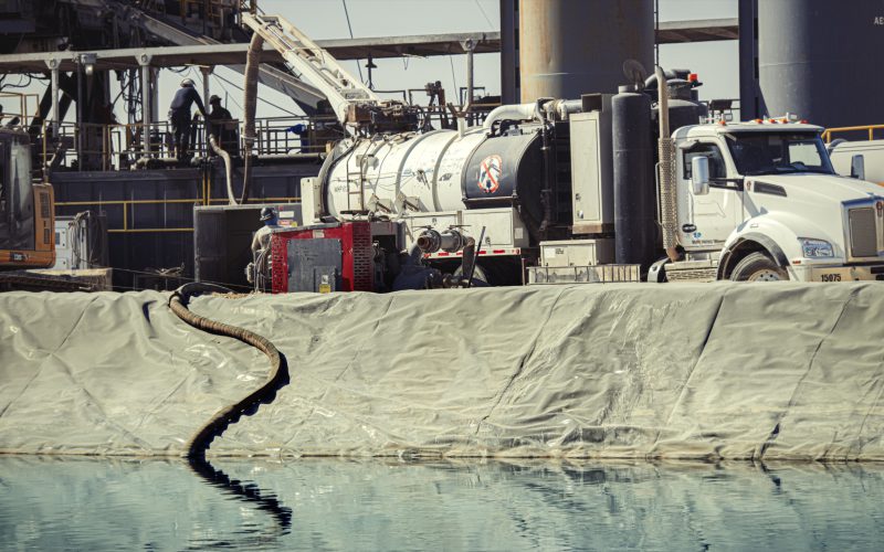 Vacuum truck working alongside a lined pit