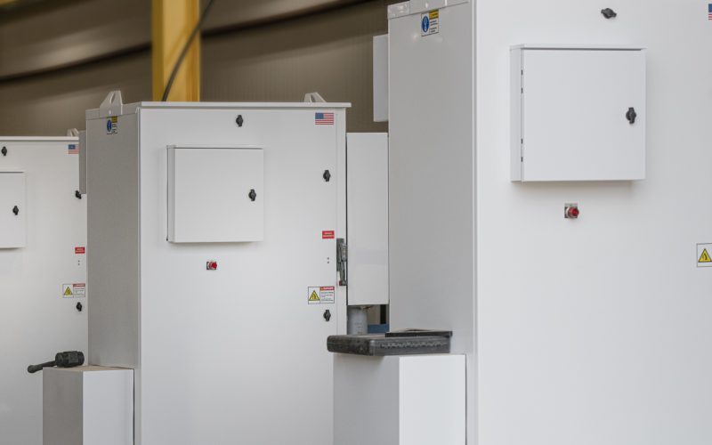 Row of white variable frequency drive control enclosures with service disconnects on the Patriot shop floor
