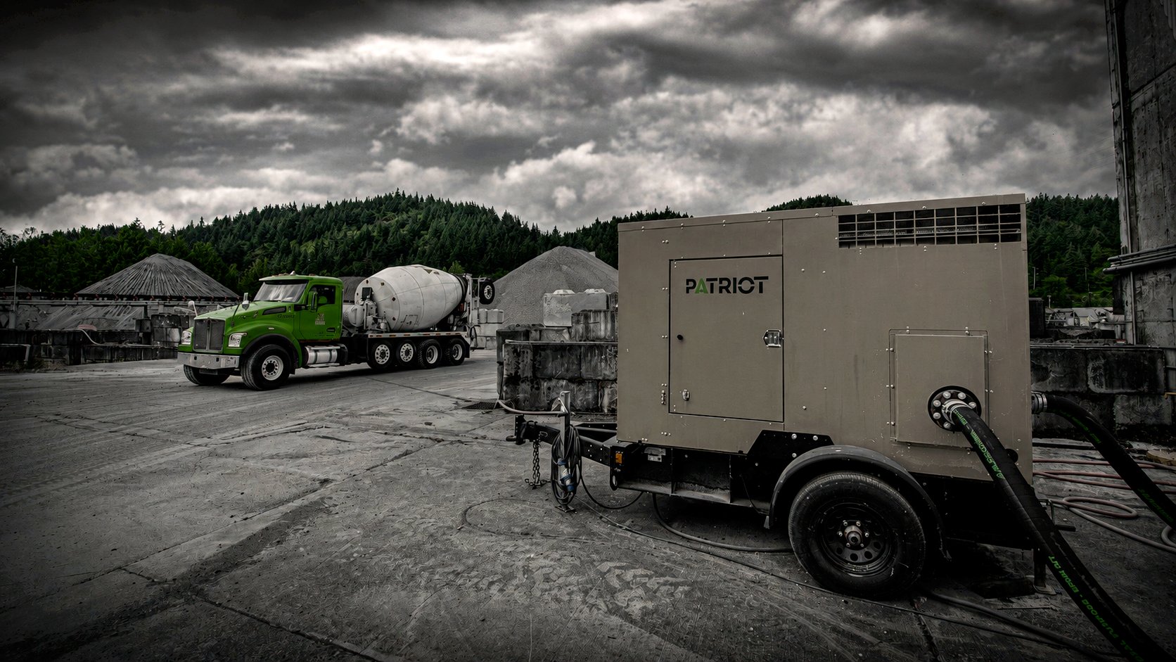 Patriot pump unit staged at a Knife River aggregate quarry as a cement mixer truck passes under a stormy sky